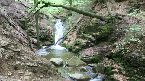 Een waterval van de Ninglinspo stroomt in een helder bassin tussen de rotsen