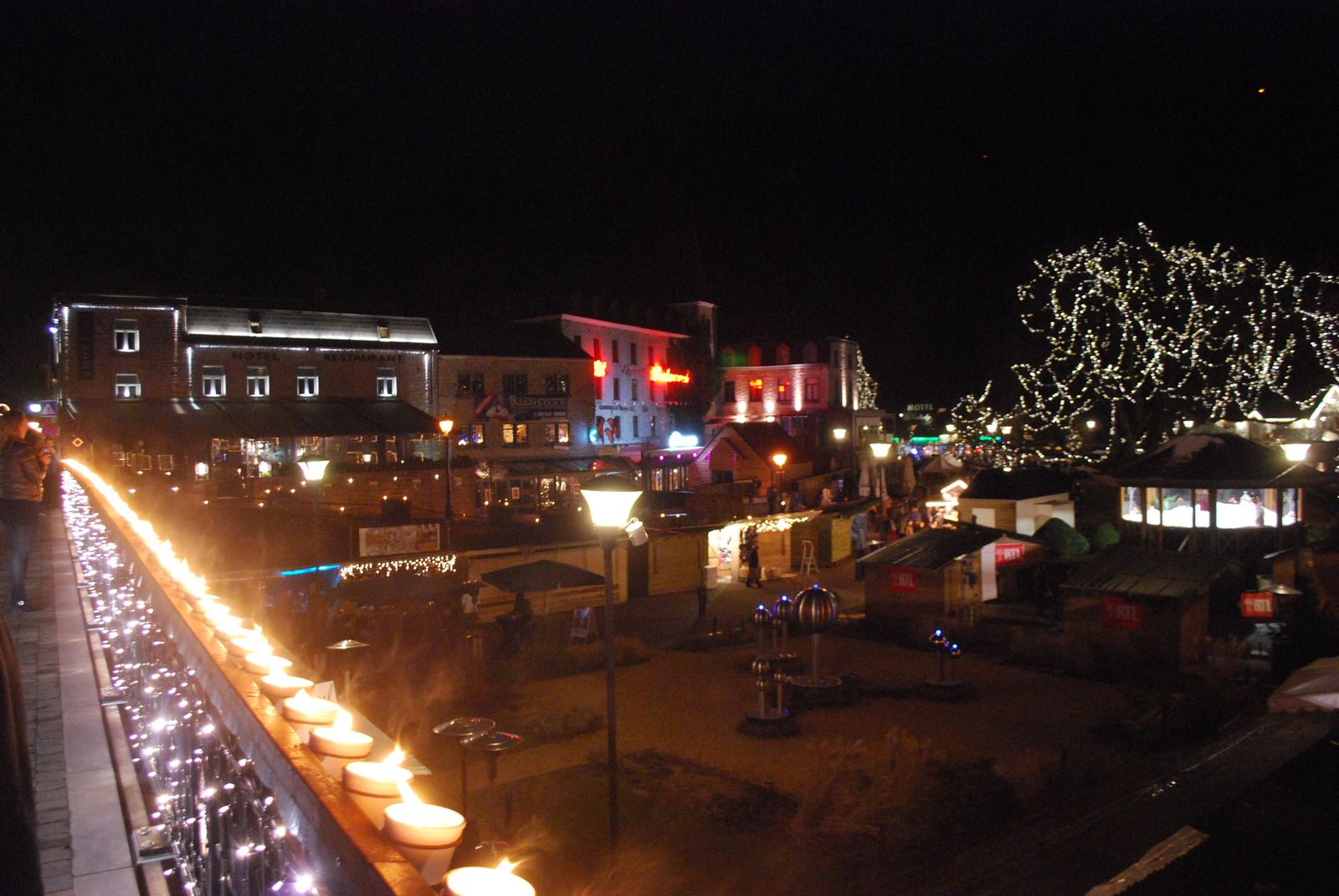 Avondsfeer op de kerstmarkt van Durbuy: een verlichte brug en kraampjes langs het water