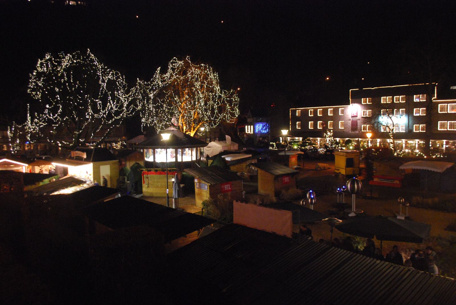 Verlichte kerstmarkt in Durbuy op kerstavond, met lichtjes in de bomen en kraampjes in het park